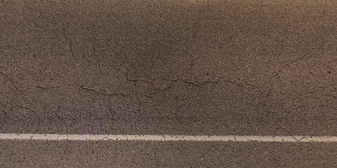 top view of surface of asphalt road made of small stones and sand with cracks