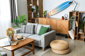 Interior of light living room with surfboard, shelving units and sofa