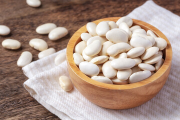 Fototapeta na wymiar Raw white beans in bowl on linen cloth