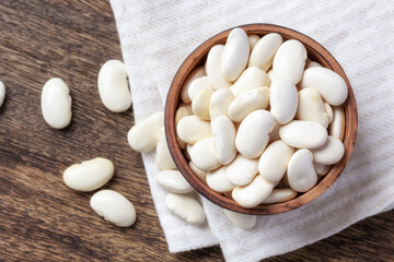 Fototapeta na wymiar White beans in wooden bowl on line cloth