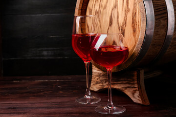 Oak barrel and glasses of wine on dark wooden background