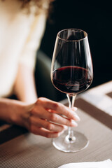 female hand holding a glass of red wine