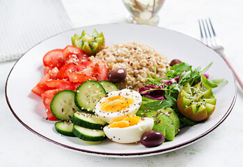 Breakfast oatmeal porridge with boiled eggs, fresh salad and kiwi. Healthy balanced food.