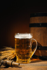 Mug of cold beer and wooden barrel on table against dark background