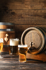 Oak barrels and glasses of cold beer on wooden background