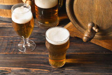 Oak barrel and glasses of cold beer on dark wooden background