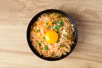 Asian instant noodle soup with fresh egg yolk on wooden background, Table top view