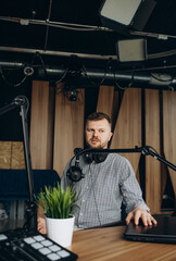 Portrait of smiling hispanic male radio presenter with clipboard hosting a show at radio station