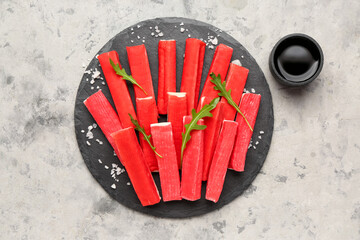 Slate board with tasty crab sticks and sauce on grunge background © Pixel-Shot