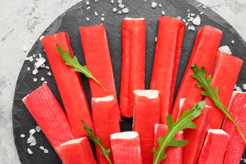 Slate board with tasty crab sticks on grunge background, closeup © Pixel-Shot