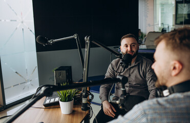 Two college podcasters laughing and having a good time in a studio. Two happy young men co-hosting...