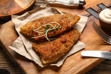 Board of tasty fried codfish on wooden background, closeup