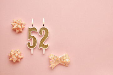 Number 52 on a pastel pink background with festive decorations. Happy birthday candles. The concept...