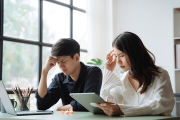 Asian couple sitting at table at home, using laptop to check documents overdue bills, taxes, debt due, bank account balance.lack of money bankruptcy, financial problems concept.