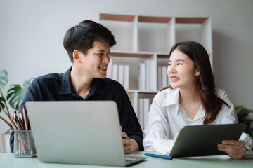 cute cheerful young couple using laptop and analyzing their finances with documents.