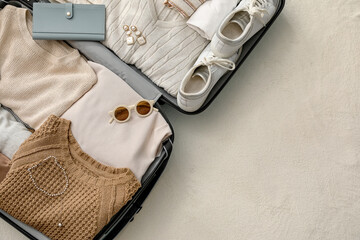 Suitcase with female clothes and accessories on white blanket