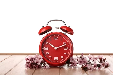 Fotobehang Blooming spring branches and alarm clock on table against white background © Pixel-Shot