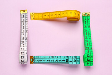 Frame made of colorful measuring tapes on pink background