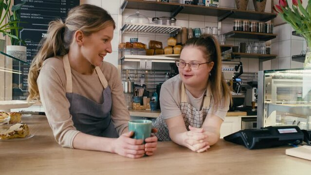 Down syndrome girl and her female workmate chatting during a short break at work. Shot with RED helium camera in 8K. 
