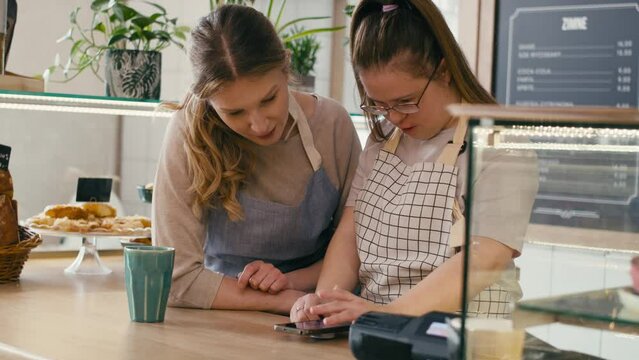 Down syndrome girl browsing phone together with her workmate in the cafe and chatting. Shot with RED helium camera in 8K. 