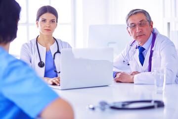 Serious medical team using a laptop in a bright office