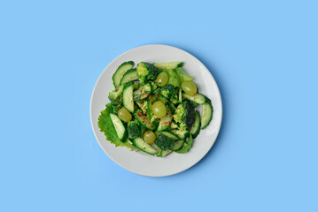 Plate with fresh salad on blue background