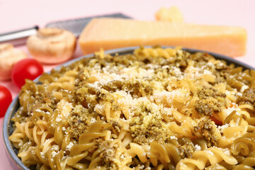 Plate of tasty Italian pasta with Parmesan cheese on pink background, closeup