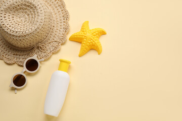 Sunscreen cream for baby with sunglasses, hat and toy on beige background