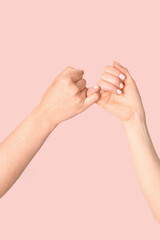 Hands of friends making pinky promise on color background