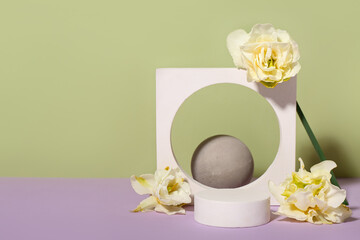 Decorative plaster podiums with flowers on violet table against green background