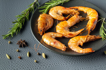 Shrimps or prawns with rosemary in a bowl on a gray table. The idea of dietary seafood for lunch or dinner