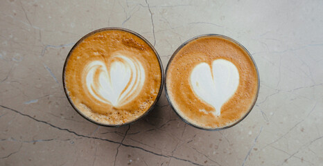 Top view of two glasses of coffee with art hearts on foam on marble background. High quality photo