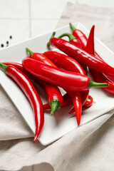 Plate with fresh chili peppers on table