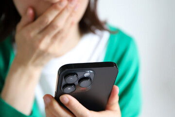 スマホを見て驚く女性