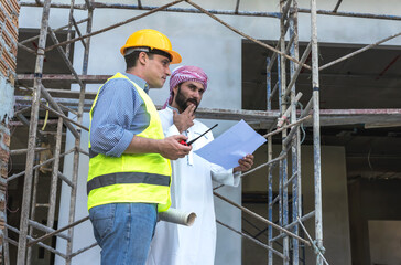 Engineer Construction standing with arab investor man looking at construction project 