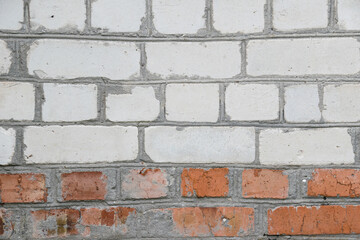 Gray background, brick wall made of white and red bricks close-up