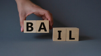 Bail symbol. Concept word Bail on wooden cubes. Businessman hand. Beautiful grey background....