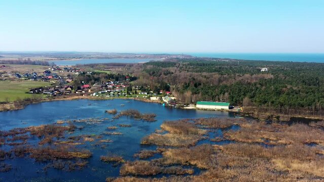 Aerial view of the small lake Konarzewo slowly silting up and overgrown with reeds with the village of Pogorzelica on the shore in Poland