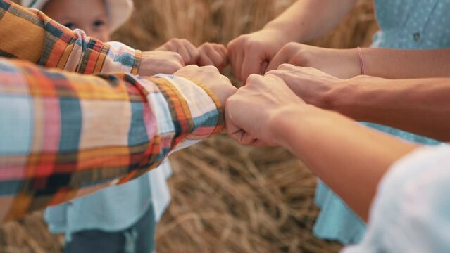Farmer family people collecting fists together making gesture of teamwork on farm. Friendship, unity with nature, farming lifestyle concept. Mom, dad, daughter and son demonstrating love care support.