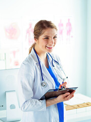 Woman doctor standing with folder at hospital.