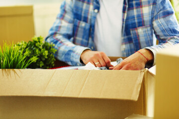 A moving man sitting on the floor in empty apartment, Among the Boxes, Checking the List of Things