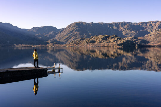 Woman with a yellow jacket looking at the horizon on a pier on a very foggy day at Lake Sanabria. Zamora, Spain.