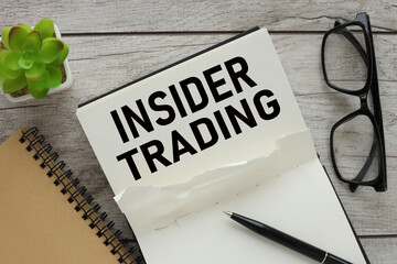 insider trading text on black notepad pages. glasses on a notebook.