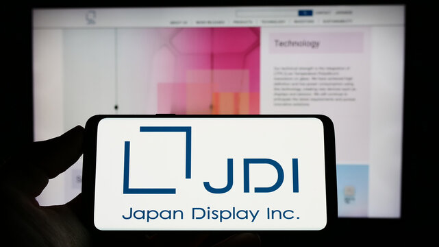Stuttgart, Germany - 04-23-2023: Person holding cellphone with logo of electronics company Japan Display Inc. (JDI) on screen in front of webpage. Focus on phone display.