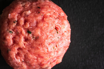 One raw beef and pork meat ball on dark background