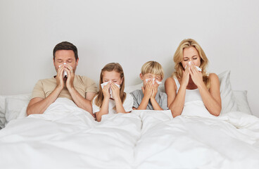 Through thick and thin. Shot of a young family looking sick in bed together.