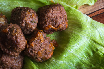 Fried cooked beef and pork meat balls on lettuce leafs closeup
