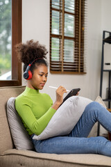 Fototapeta premium An American teenage woman is in the living room, she is spending her weekends at home playing social media and watching movies. The concept of living on vacation.