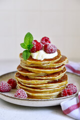 Delicious homemade pancakes with whipped cream, maple syrup and raspberry for a breakfast.