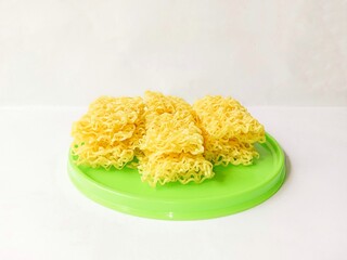 Raw dry yellow noodles served with green plate isolated on white background